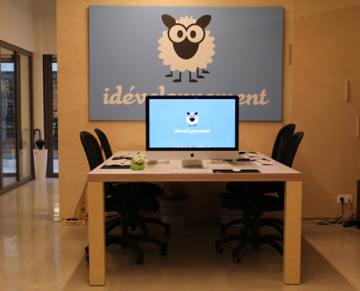 Photo d'un espace de travail avec un iMac et le logo d'idéveloppement